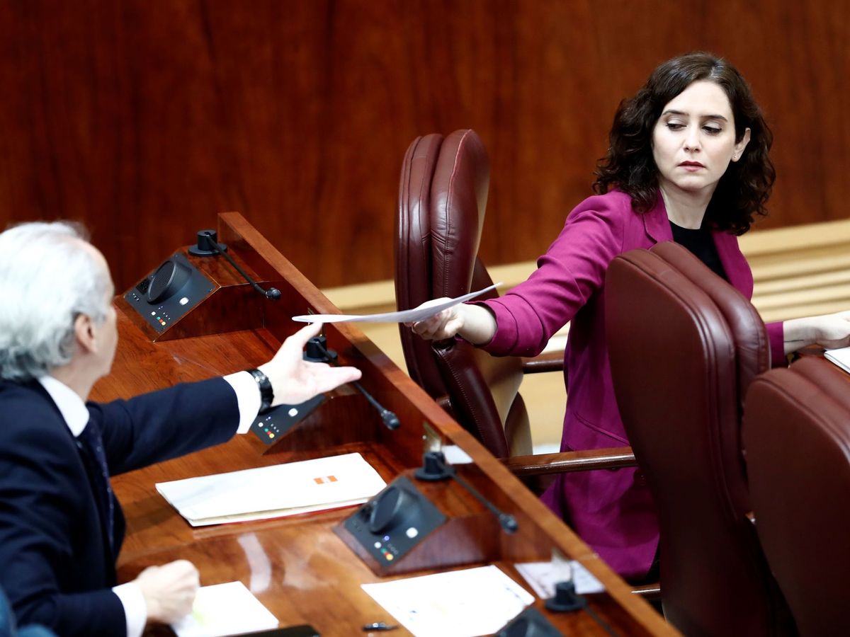 Foto: La presidenta de Madrid, Isabel Díaz Ayuso, entrega un papel al consejero de Sanidad, Enrique Ruiz Escudero, este 14 de mayo en la Asamblea. (EFE)