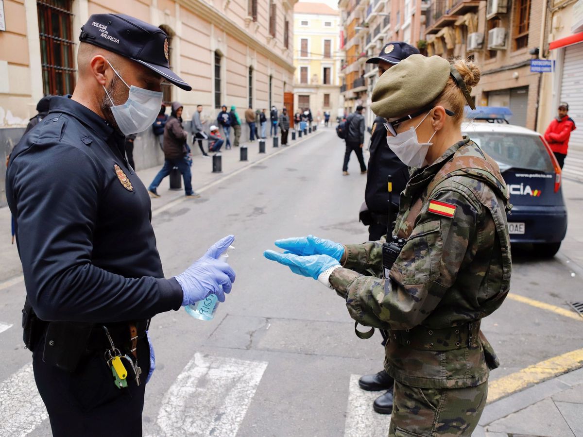 Foto: Un Policía Local de Murcia ofrece gel desinfectante a una militar del Ejército de Tierra. (EFE)
