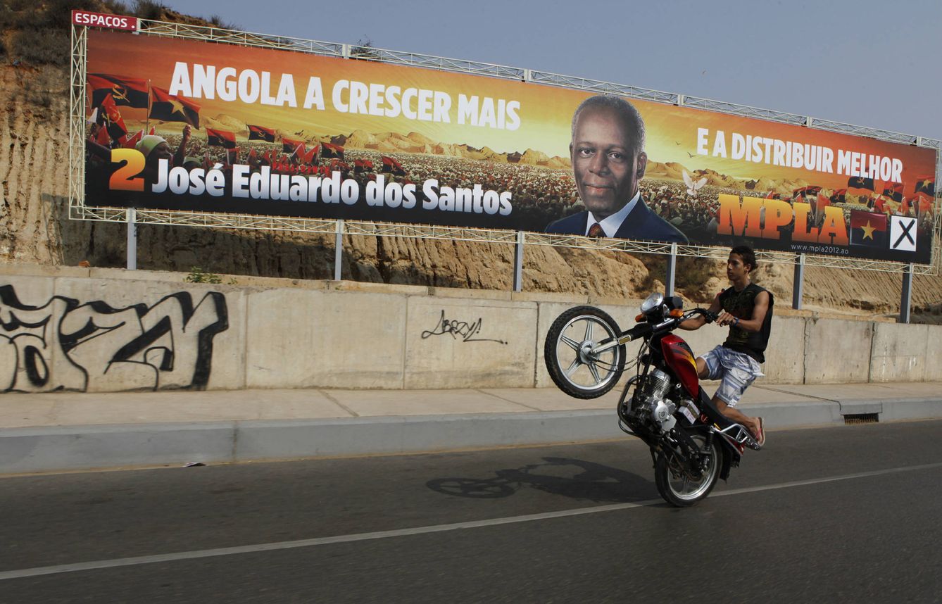 Un motociclista pasa delante de un poster de Dos Santos en Luanda, en 2012. (Reuters)