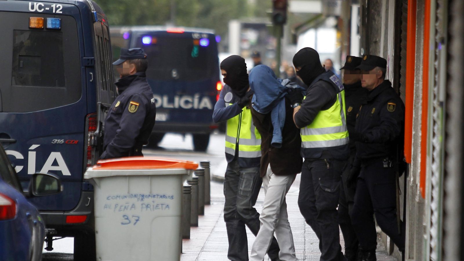 Foto: Dos efectivos de la Policía acompañan a la persona detenida en el madrileño barrio de Vallecas. (EFE)