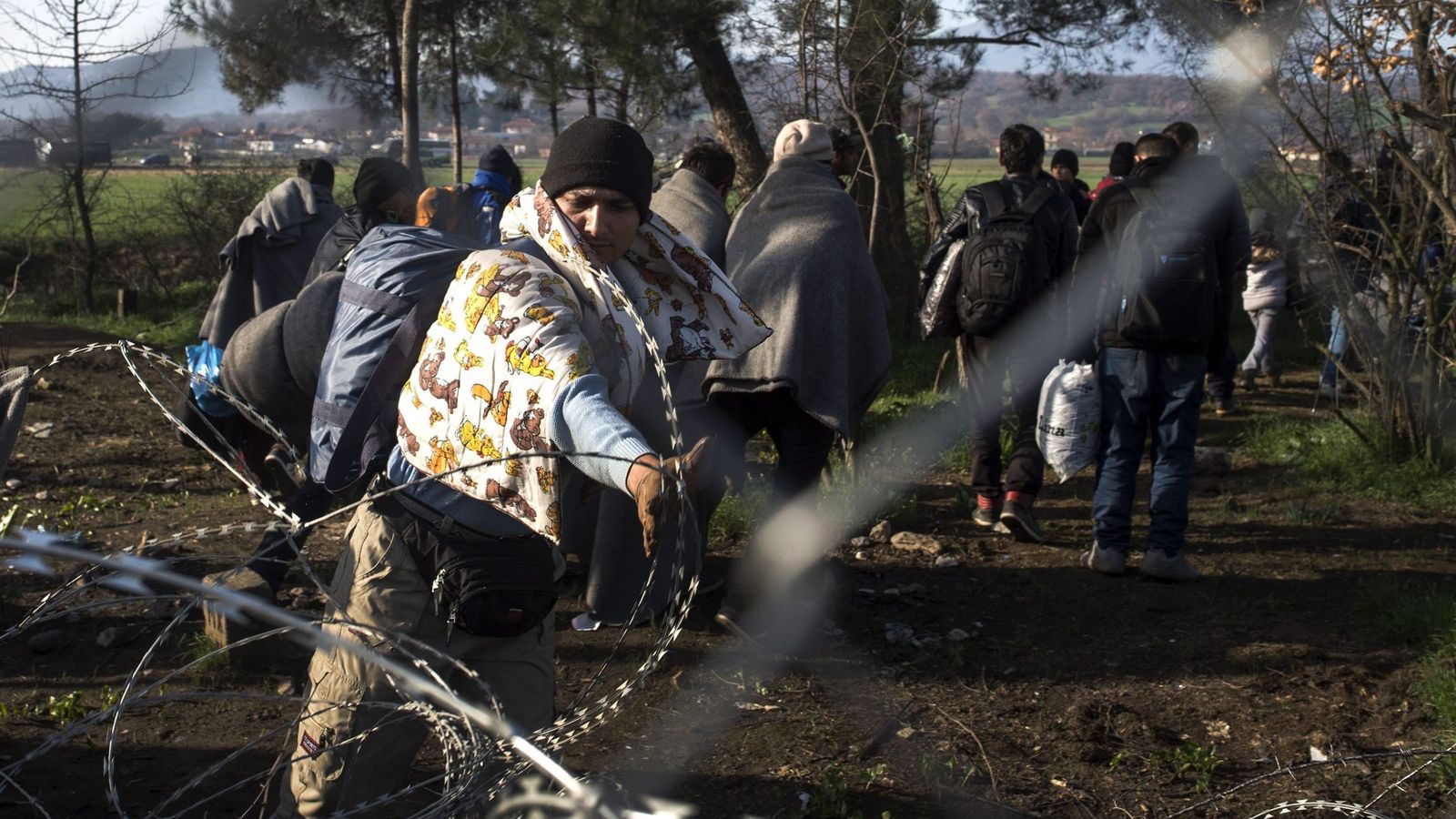 Foto: Un migrante afgano intenta retirar una alambrada en la localidad fronteriza de Gevgelija, Macedonia. (EFE)