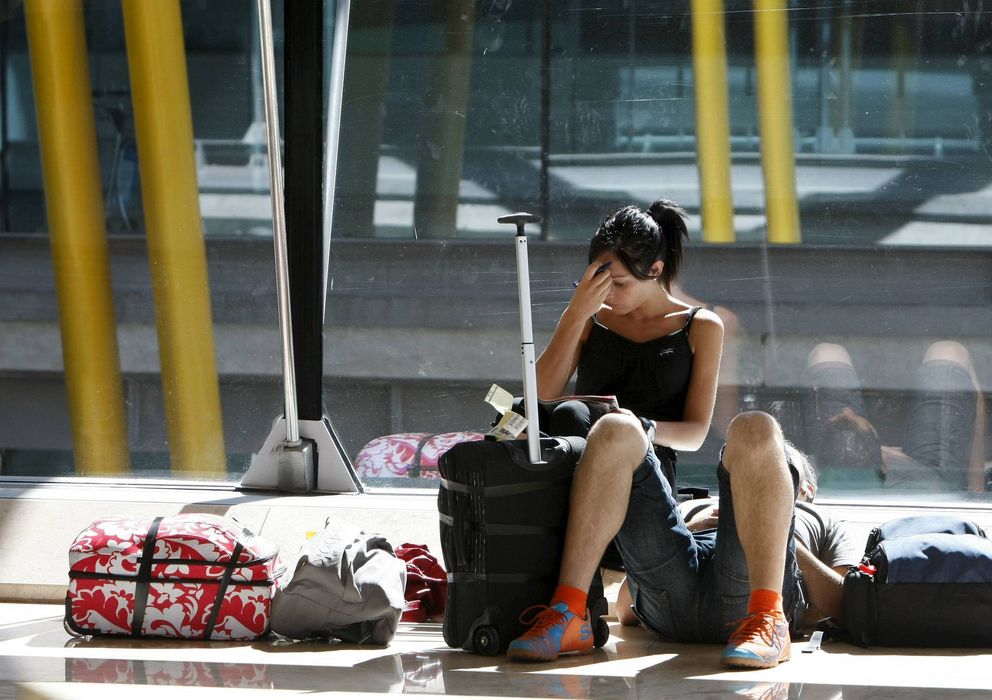 Foto: Una mujer descansa en el suelo junto a su equipaje en el aeropuerto de Barajas. (2010)
