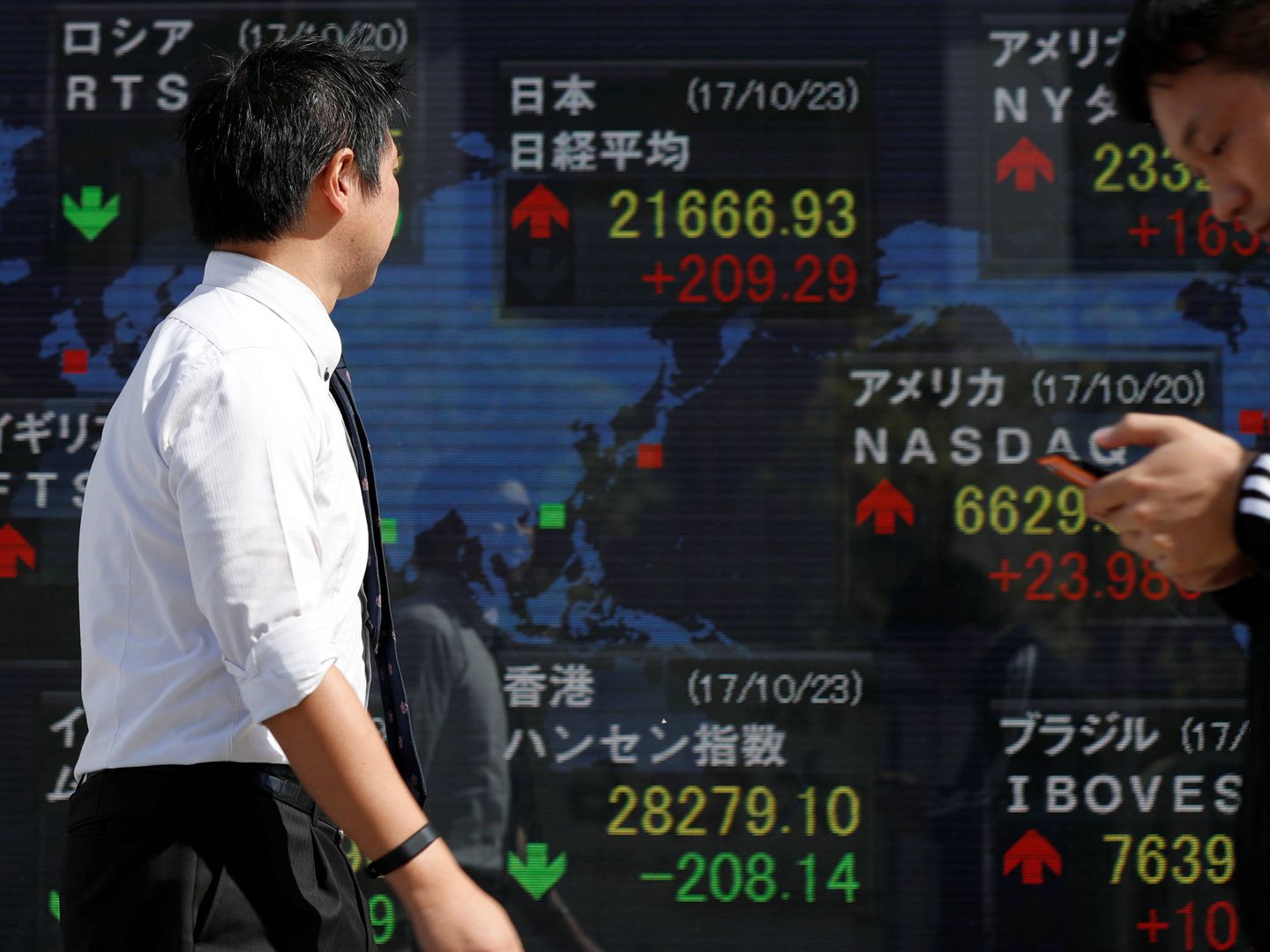 Japoneses pasan ante una pantalla con las cotizaciones de bolsa, en Tokio. (Reuters)