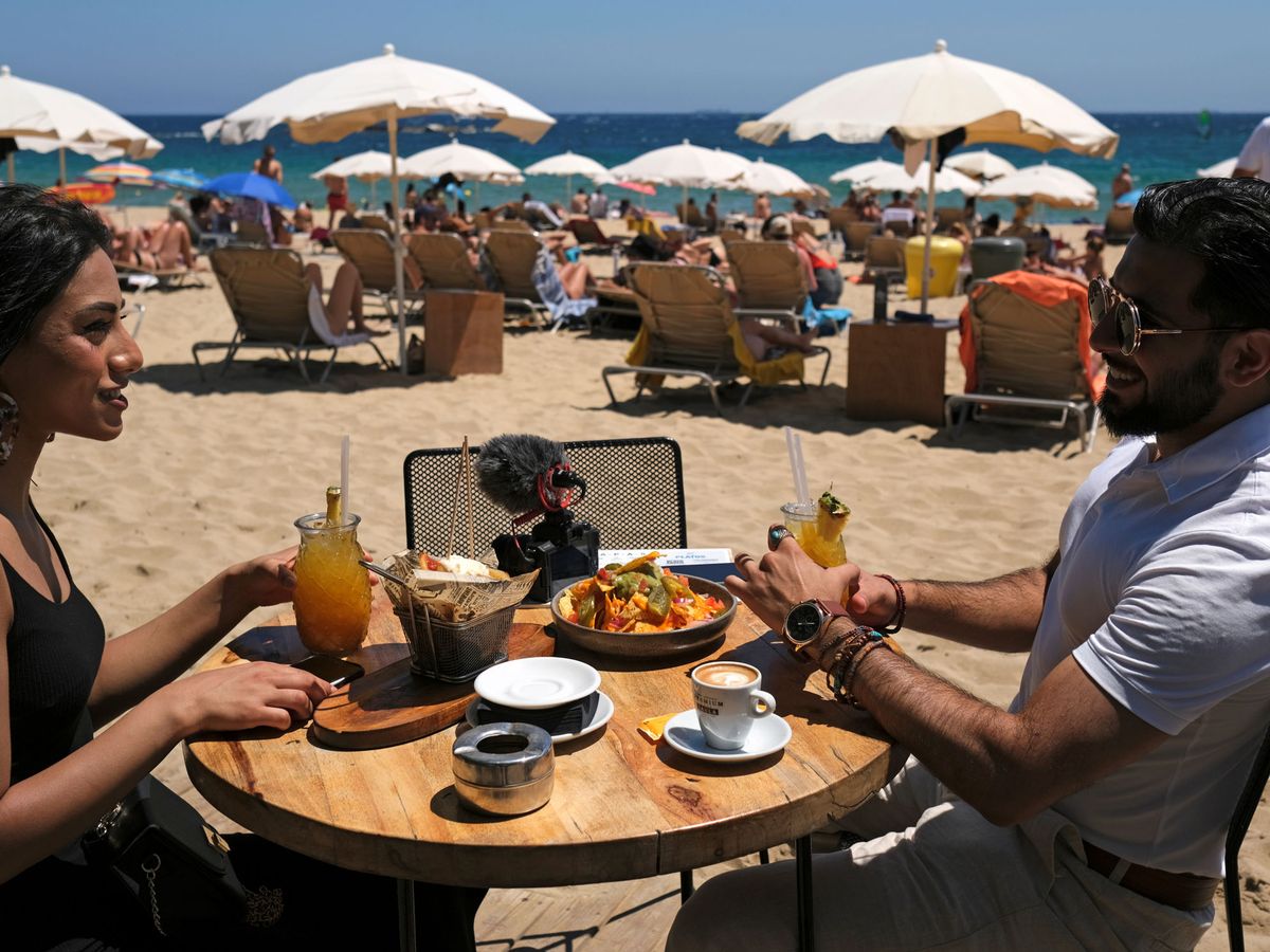 Foto: Dos jóvenes comen en la playa de la Barceloneta. (Reuters)