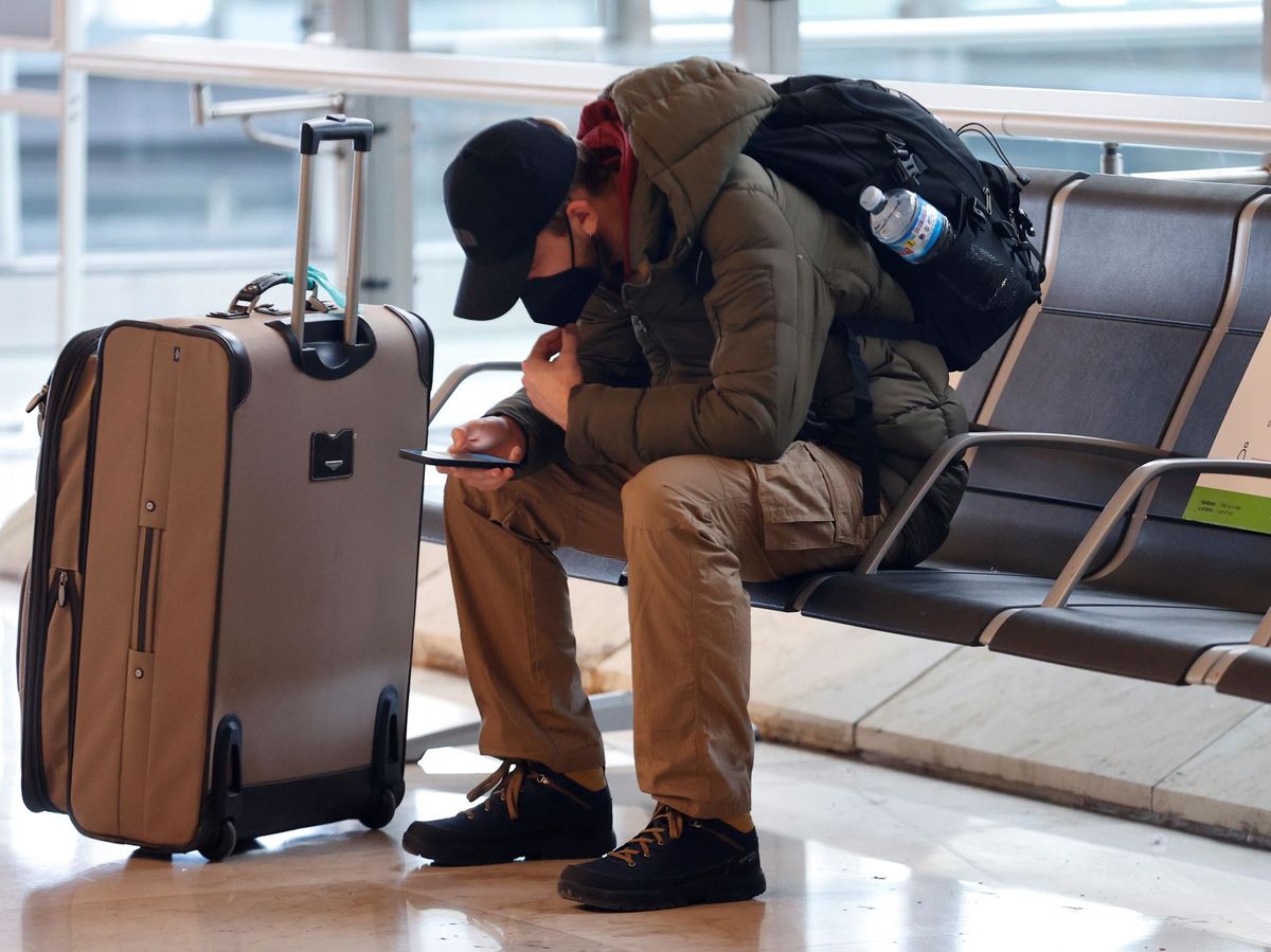 Foto: Un viajero revisa su teléfono en el aeropuerto Adolfo Suárez Madrid-Barajas. (EFE)