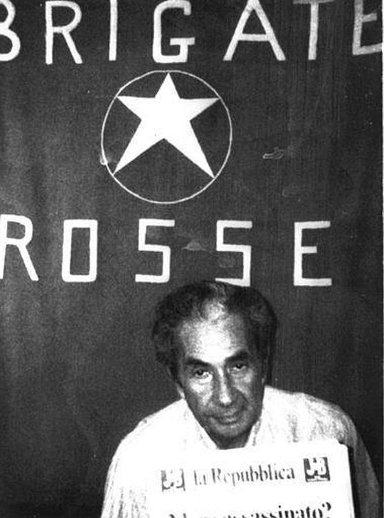 Aldo Moro en el lugar del secuestro junto a la bandera de las Brigadas Rojas.