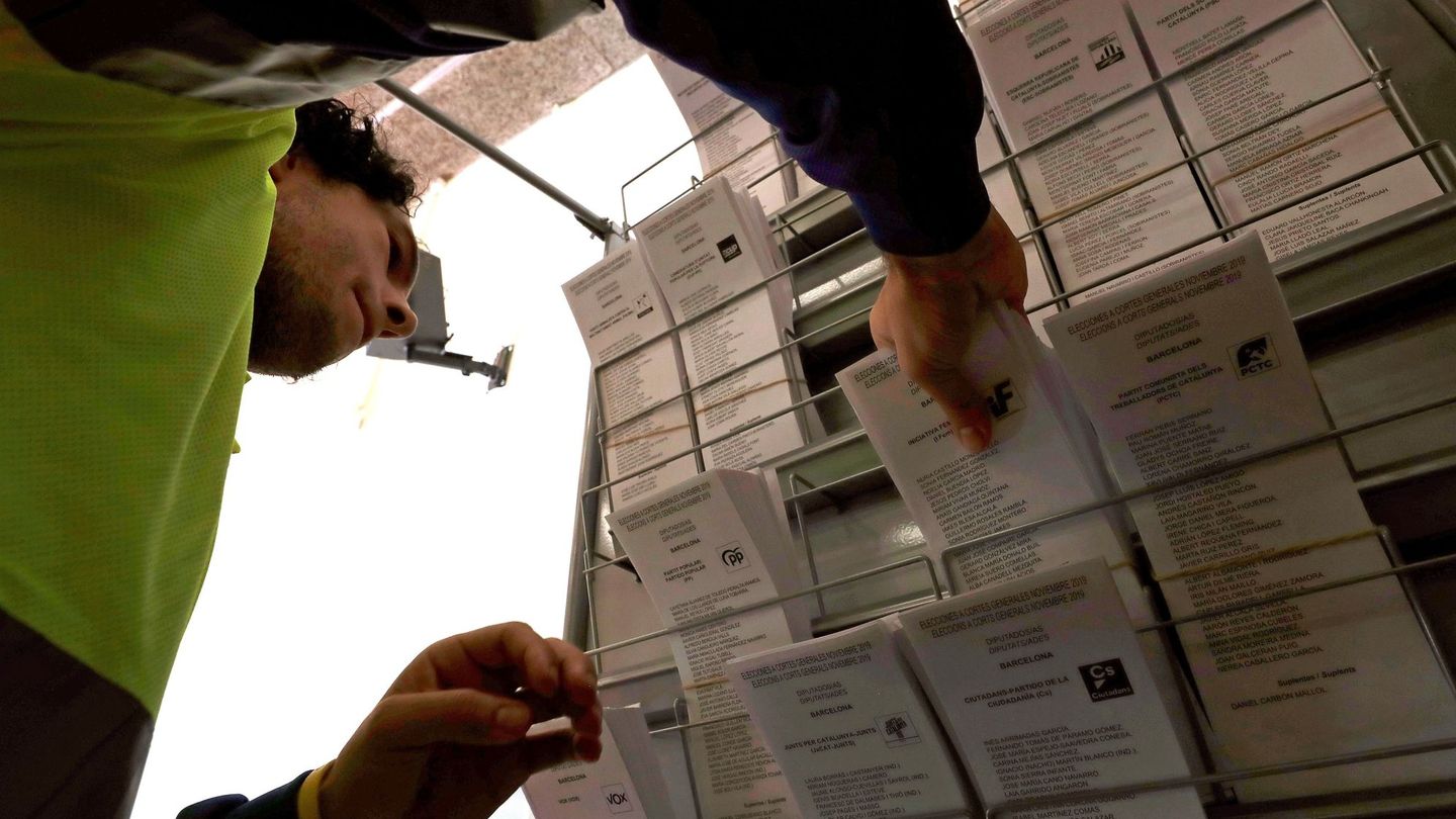 Un operario coloca papeletas electorales en una cabina en un colegio de Barcelona (EFE)