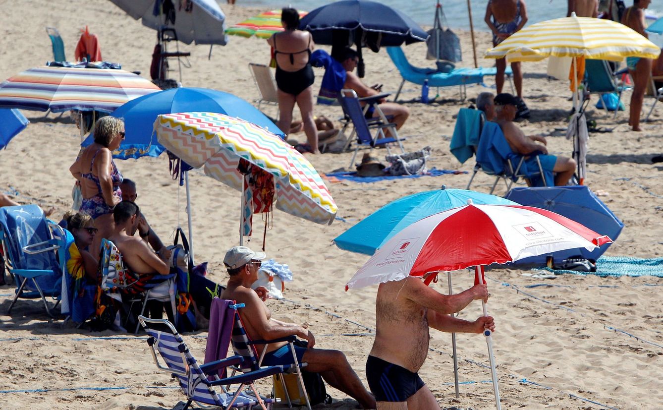 Varias personas colocan la sombrilla en una playa (EFE)
