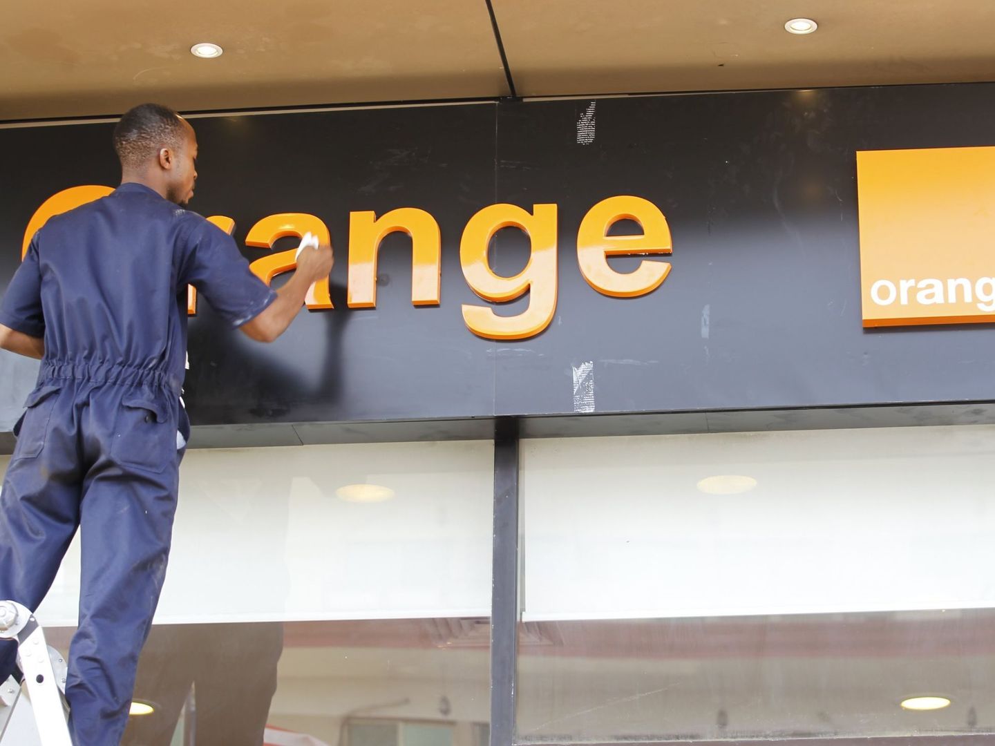 Un operario limpia un cartel de Orange. (Foto: Efe)