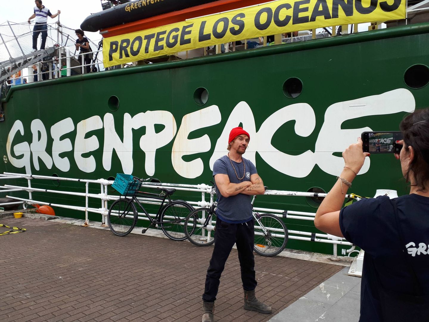 Macaco pide a una integrante de Greenpeace que le fotografíe delante del barco 'Arctic Sunrise'. (J. M. A.)
