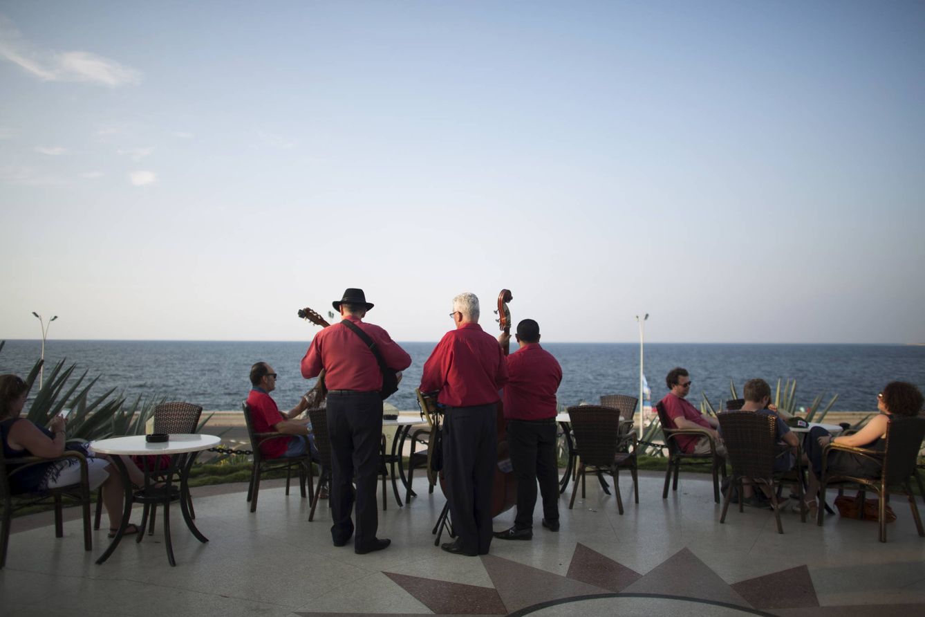 Músicos cubanos tocan temas tradicionales mientras unos turistas disfrutan del atardecer en un hotel de La Habana (Reuters).