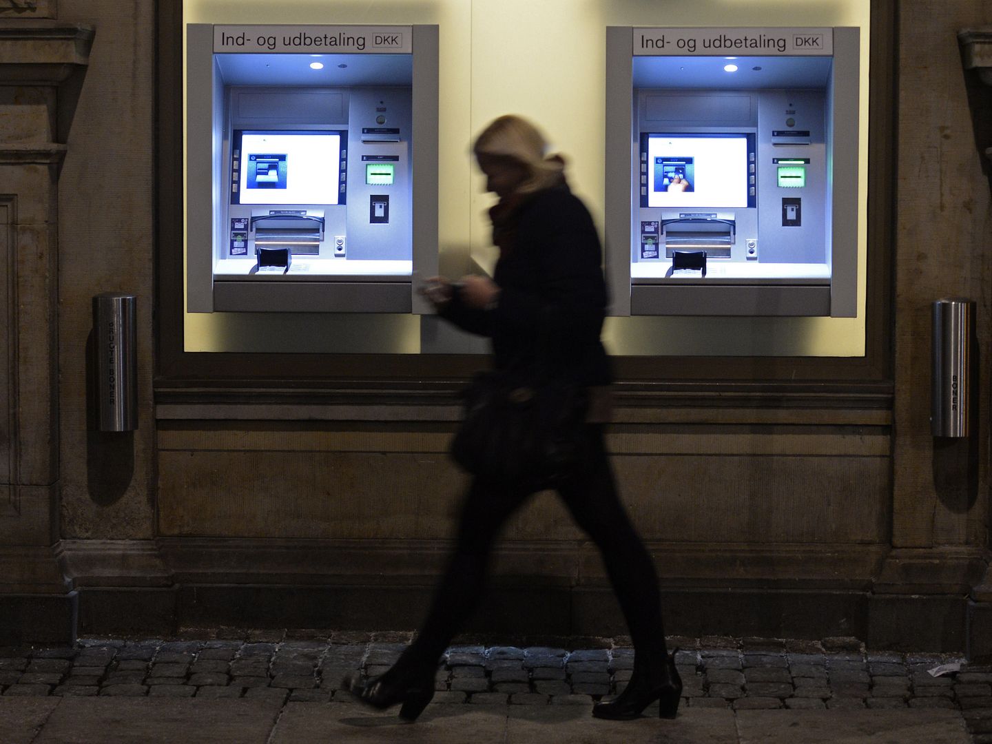 Una mujer pasa por delante de dos cajeros automáticos en Copenhague, Dinamarca, el 22 de enero de 2015 (Reuters)