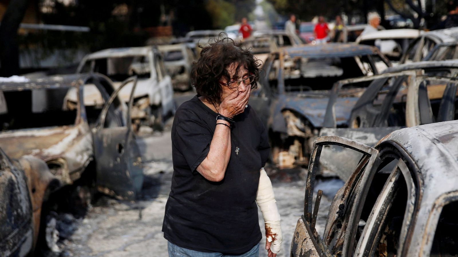 Foto: Una mujer herida se tapa la boca mientras trata de encontrar a su perro tras el incendio en Mati, cerca de Atenas, el 24 de julio de 2018. (Reuters)