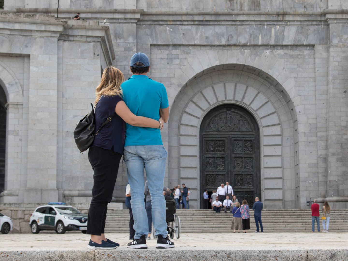 Dos visitantes se abrazan frente a la entrada a la basílica de la Santa Cruz