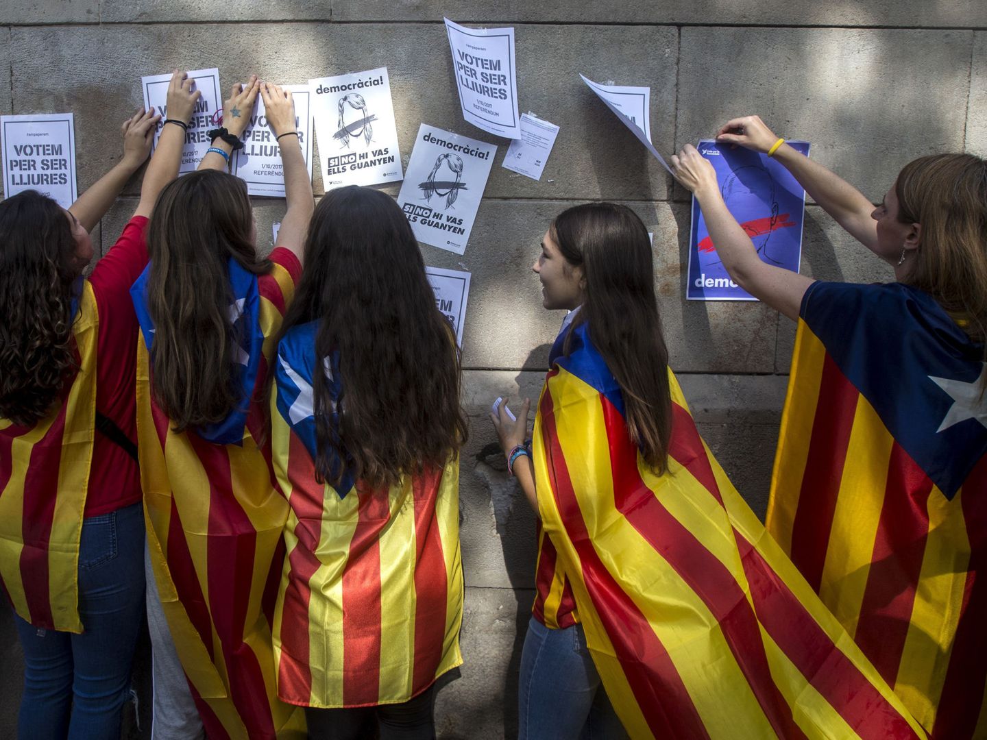 Varias estudiantes enganchan carteles en la pared de la Universidad de Barcelona. (EFE)