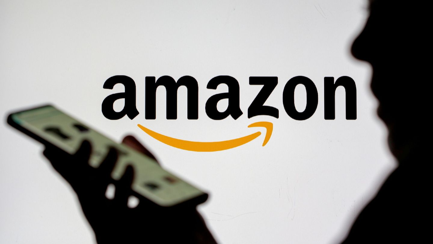 Una mujer consulta su teléfono frente al logo de Amazon. (Reuters/Dado Ruvic)