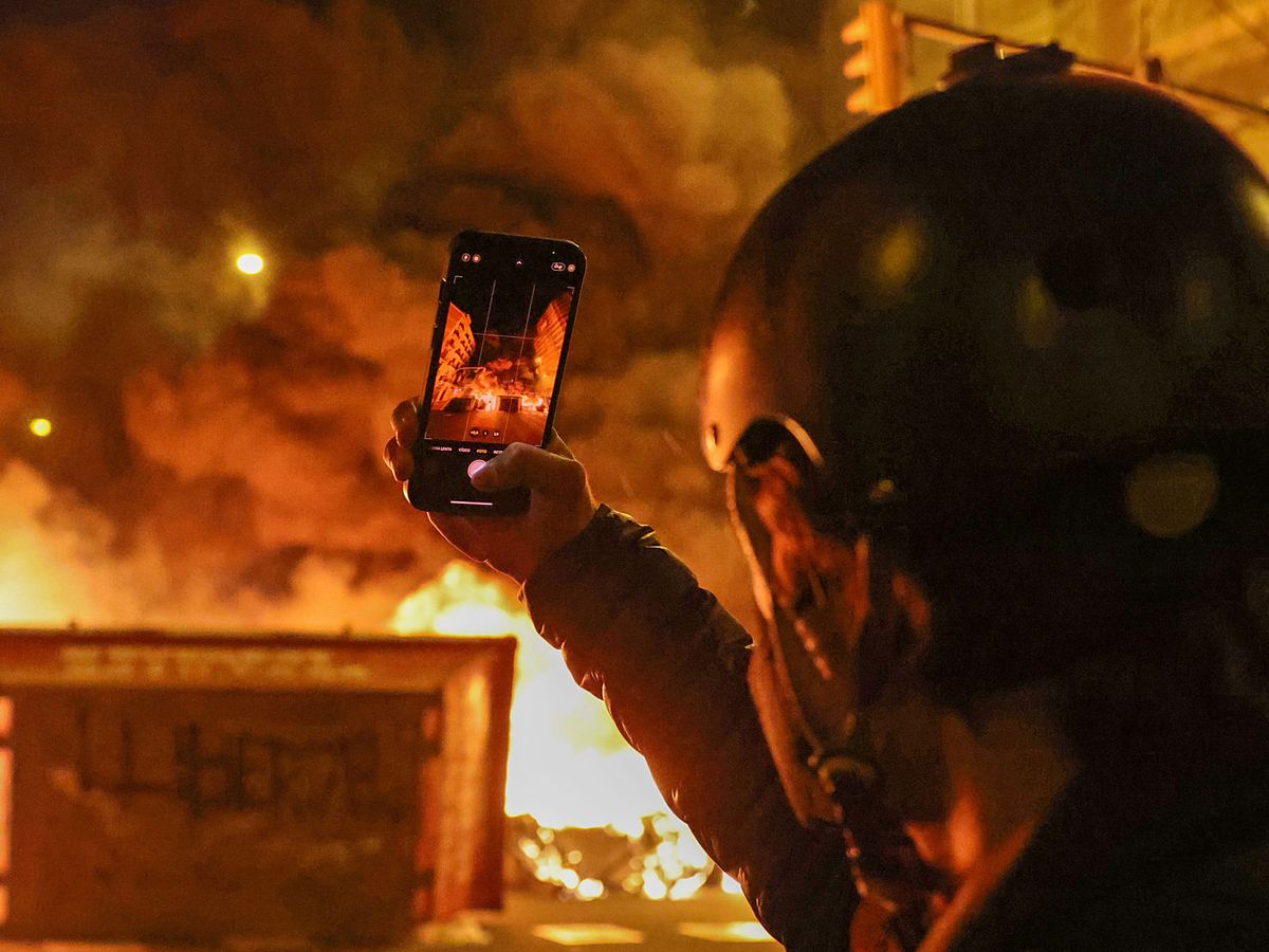 Foto: Un hombre utiliza su teléfono móvil para tomar una foto de una barricada en Barcelona. (Reuters/Nacho Doce)
