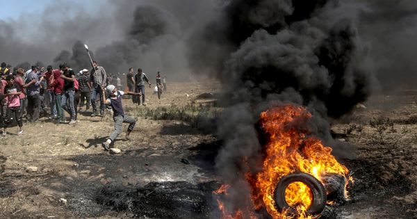 Foto: Manifestantes lanzan piedras contra soldados israelíes durante unas protestas en la frontera de Gaza e Israel, el 14 de mayo de 2018. (EFE)