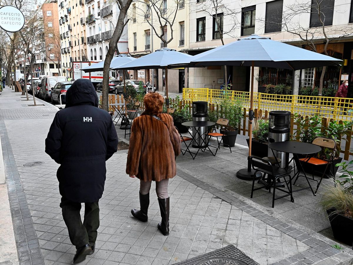 Foto: Varias personas pasan junto a la terraza de un bar instalada en la calle Alonso Cano de Madrid. (EFE/Fernando Villar)