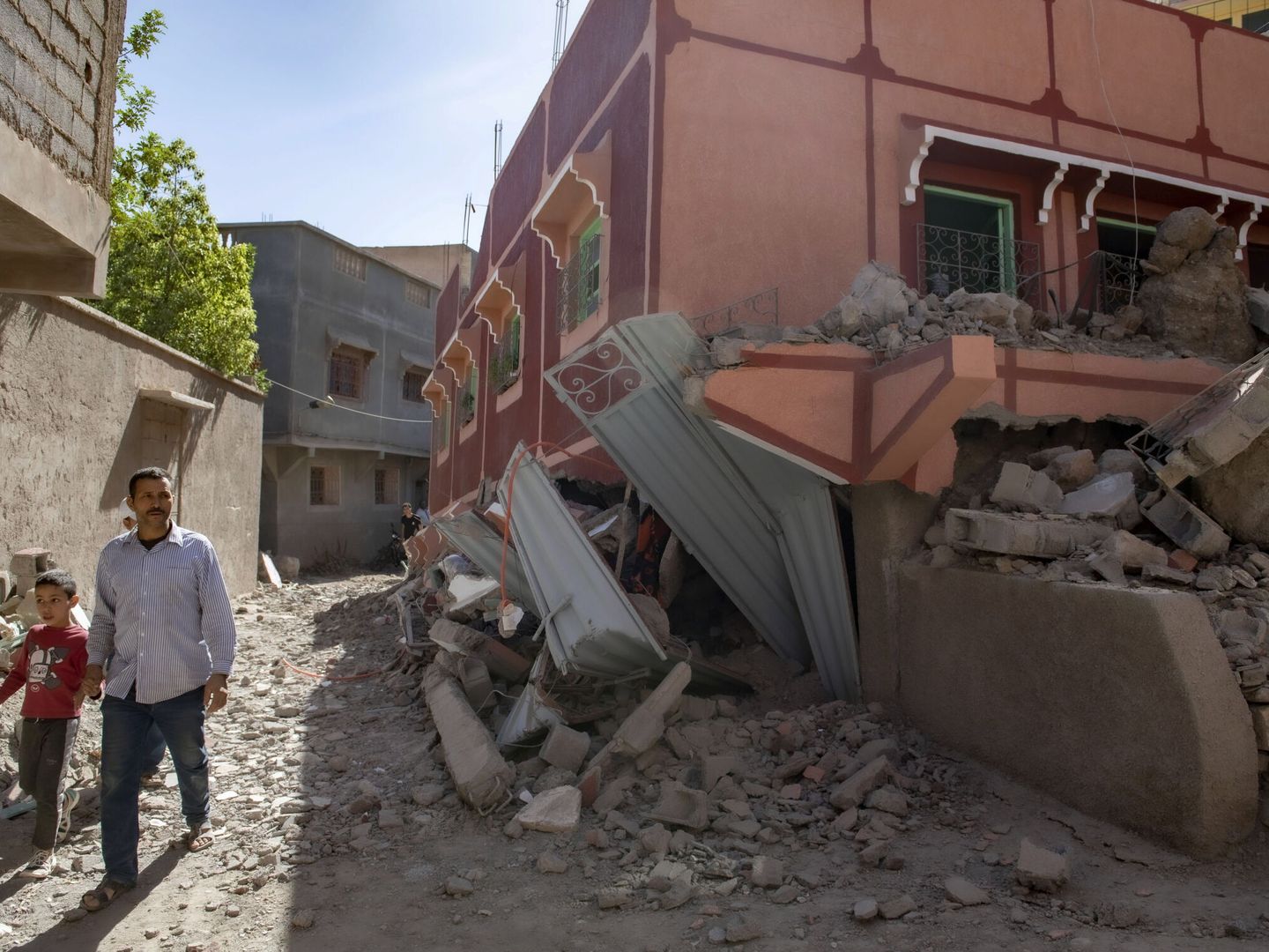 Una persona con un niño camina junto a un edificio dañado tras el terremoto en Marrakech. (EFE/Jalal Morchidi) 