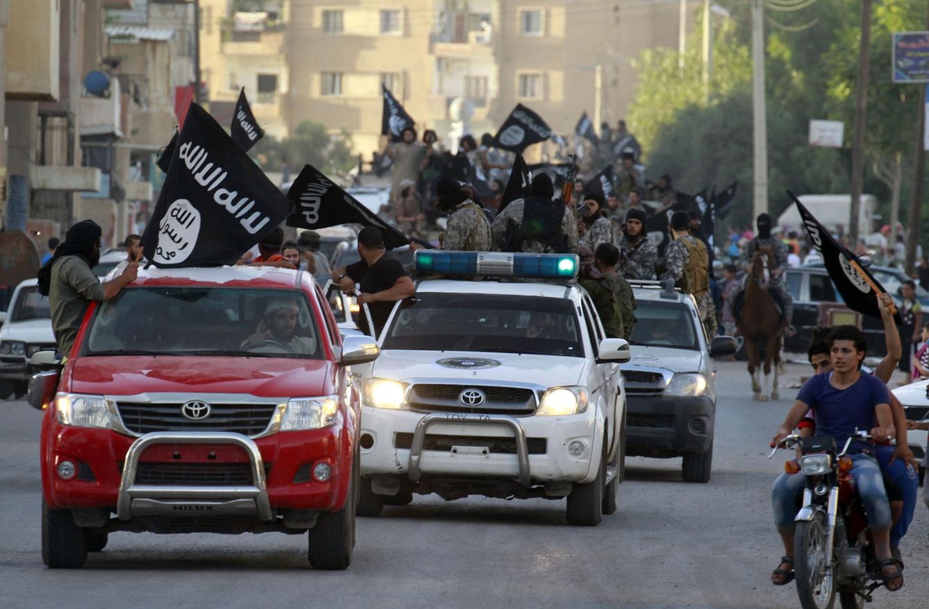 Militantes del ISIS ondean banderas del grupo durante un desfile militar en Raqqa, Siria (Reuters).