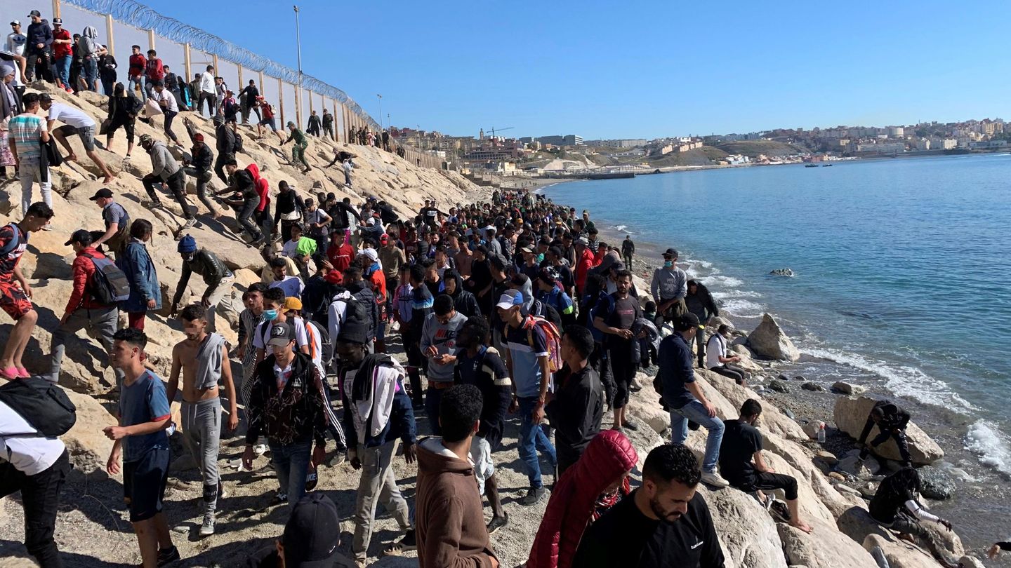 Un grupo de personas trata de cruzar la valla fronteriza que separa Fnideq (Castillejos, Marruecos) y Ceuta. (EFE)