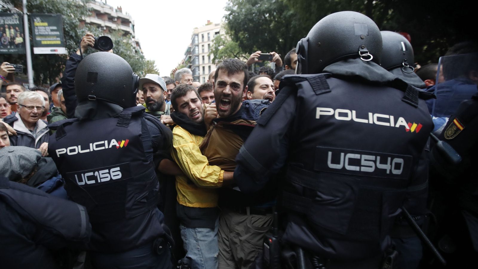 Foto: Agentes antidisturbios de la Policía Nacional forman un cordón de seguridad frente al colegio Ramón Llull de Barcelona el 1-O. (EFE)