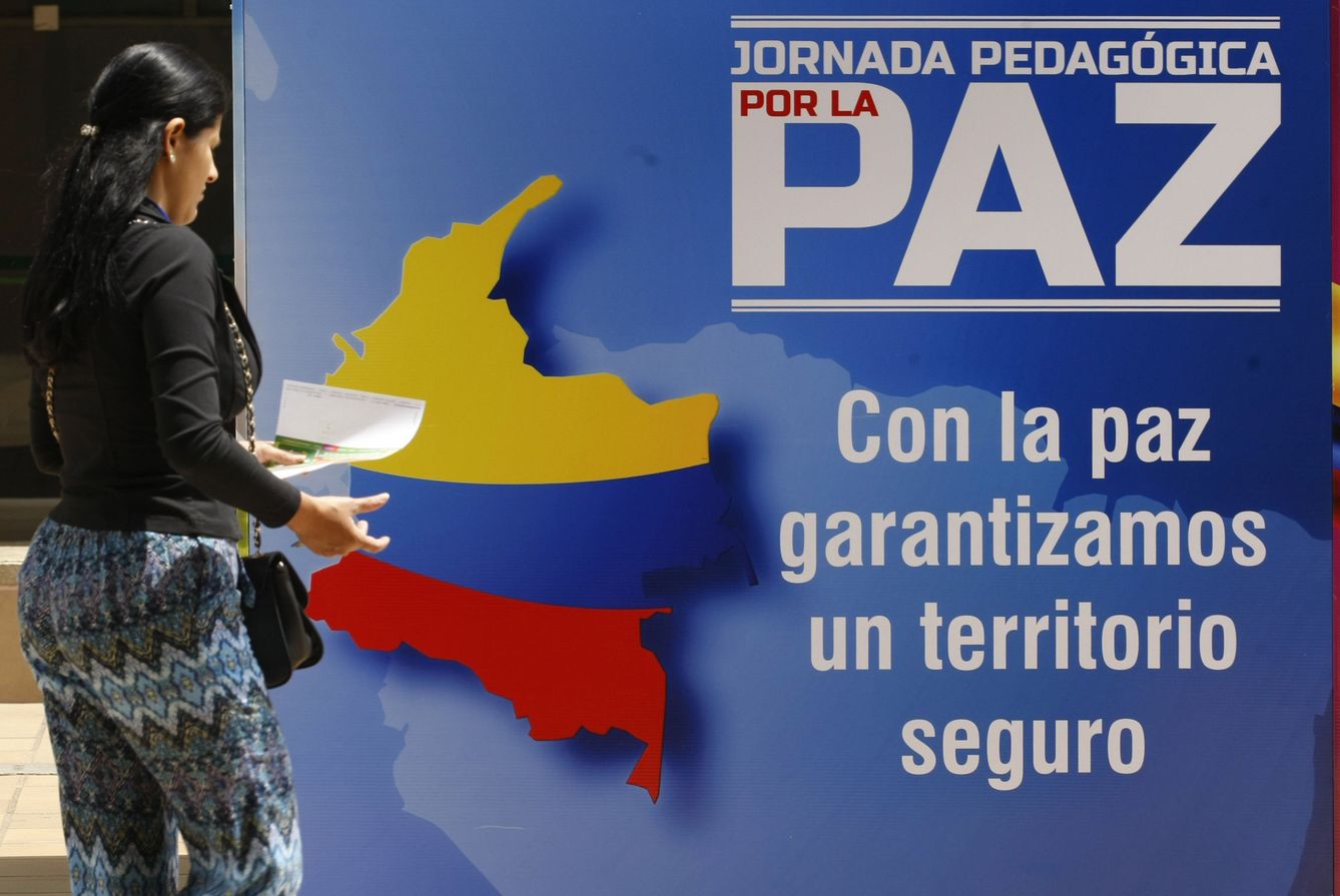 Una mujer pasa junto a una pancarta que invita a una jornada pedagógica por la paz. (EFE)
