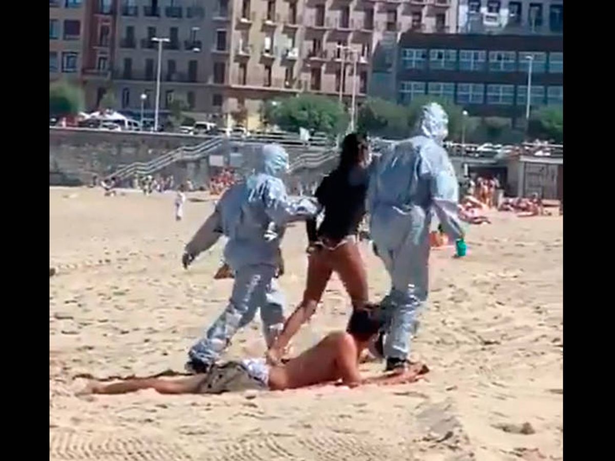 Foto: La policía se llevó a la surfera esposada de la playa ante la atónita mirada de los bañistas (Foto: Twitter/JavierSanz)