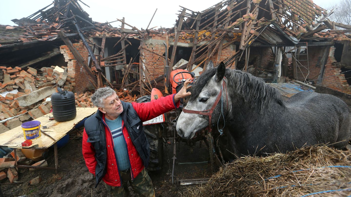 Un granjero cuida de su caballo en medio de las ruinas de una casa (REUTERS)