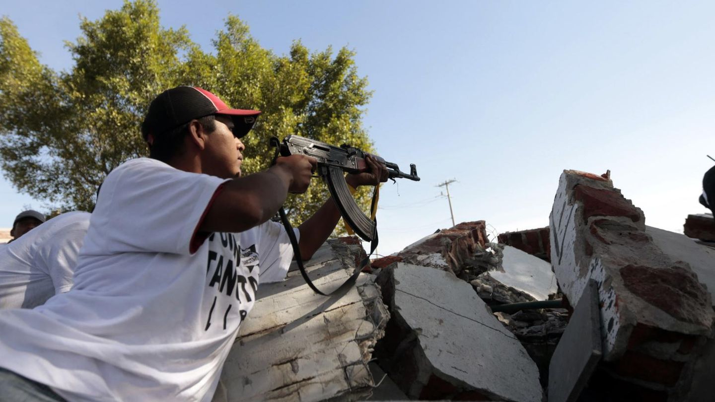 Una autodefensa se protege tras entrar en Paracuaro, en Michoacán (Reuters).