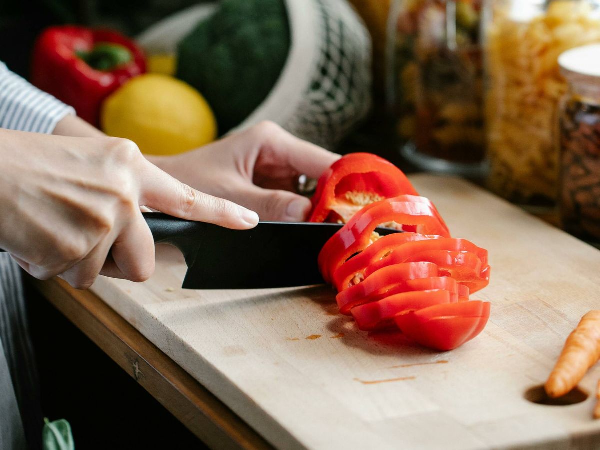 Foto: Una persona cortando verduras como parte de una comida (Pexels)