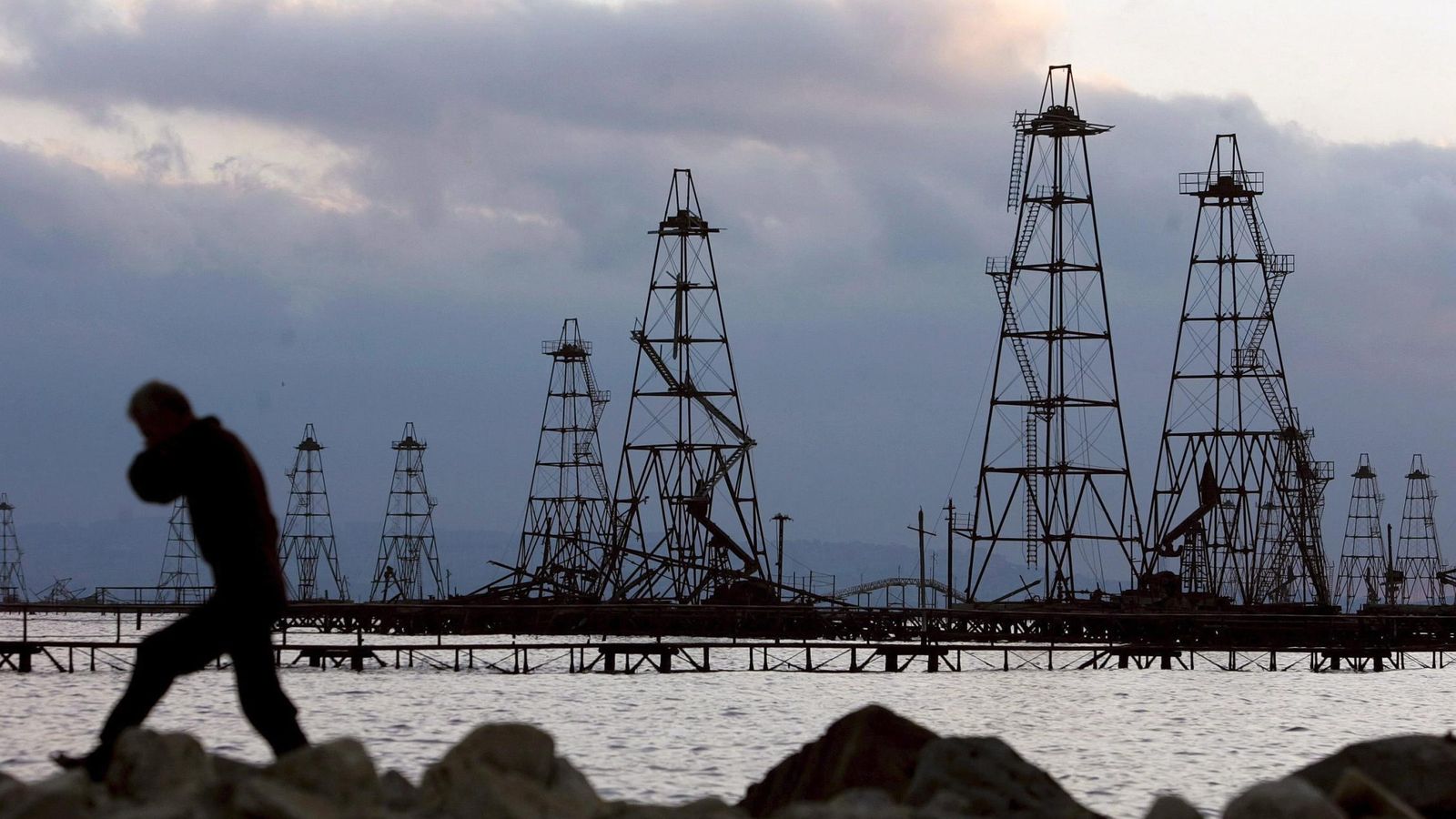 Foto: Un trabajador pasa frente a unas torres de extracción de crudo en el Mar Caspio, cerca de Bakú, Azerbaiyán (EFE)