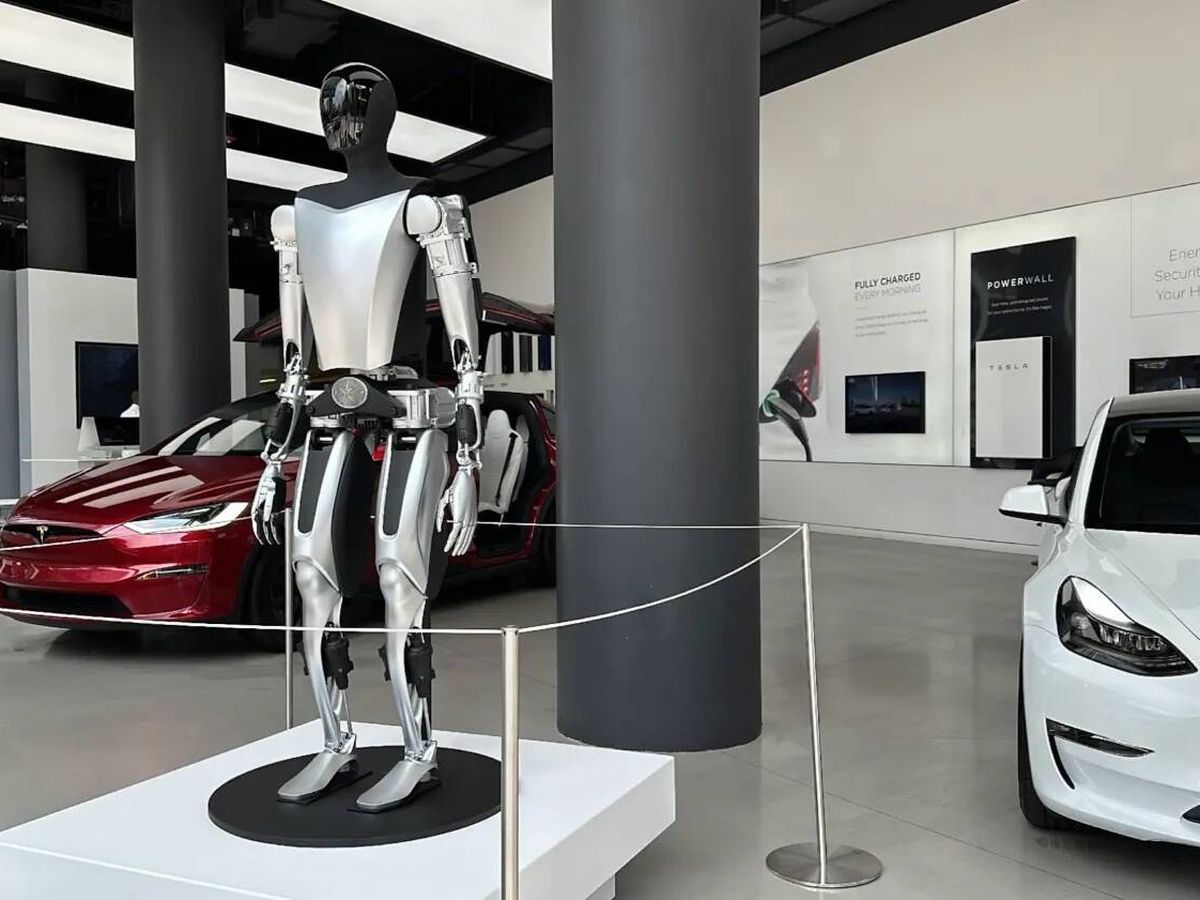 Foto: Un robot junto a distintos modelos de Tesla. (Cedida)