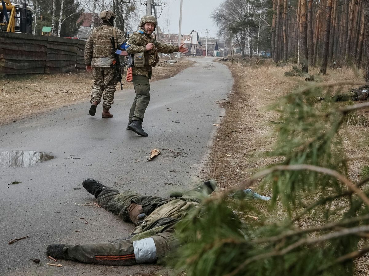 Foto: Soldados ucranianos caminan cerca de cuerpos de soldados rusos muertos en el frente cerca de Kiev. (Reuters/Gleb Garanich)
