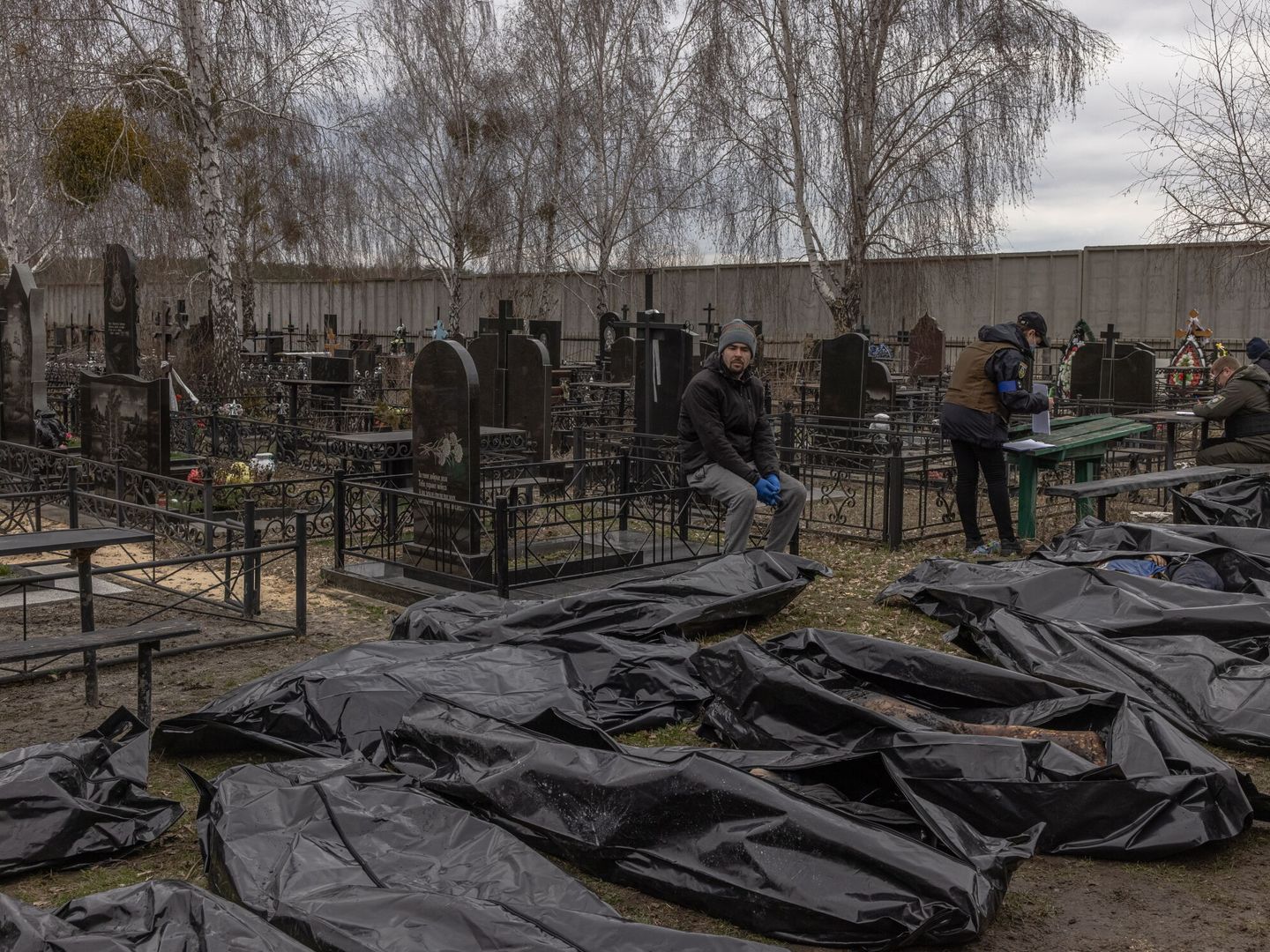 Un hombre mira a las decenas de cadáveres que fueron llamados al cementerio durante el proceso de identificación en Bucha tras la retirada de las tropas rusas. (EFE/ROMAN PILIPEY)