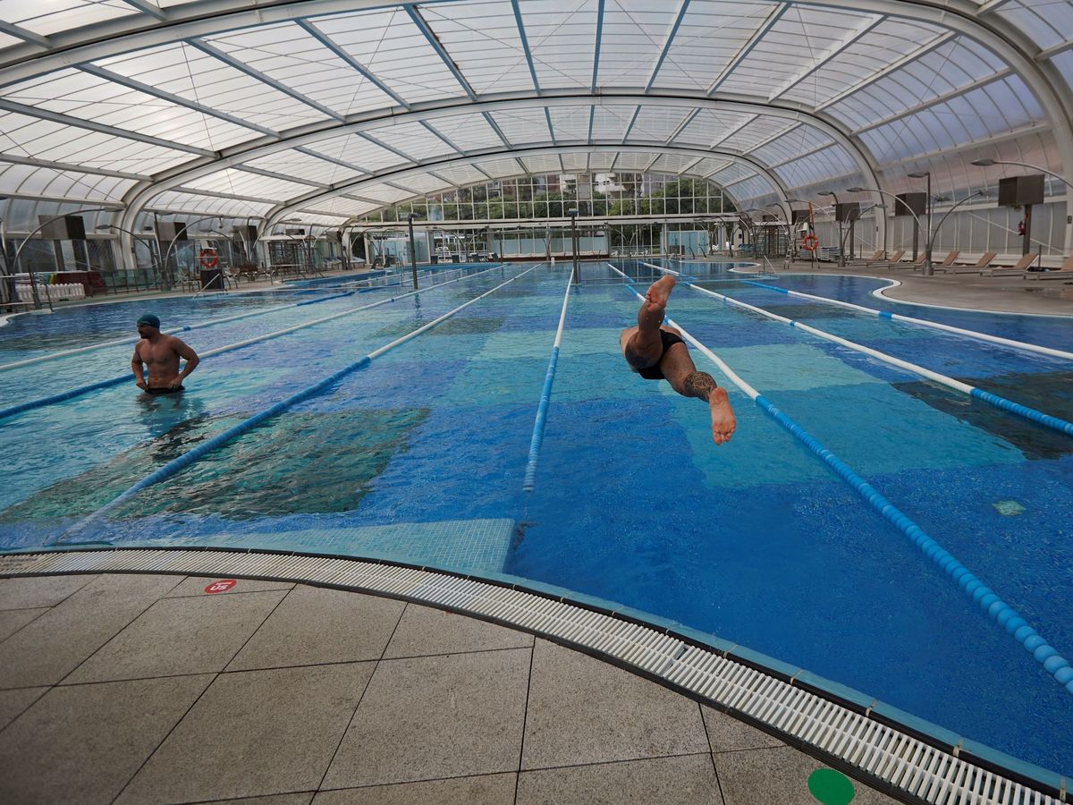 Foto: Dos personas mantienen la distancia de seguridad en la piscina del gimnasio DiR Diagonal. (EFE)