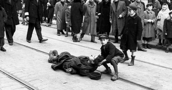 Foto: Un niño ayuda a un hombre desmayado en las vías por las que pasaba el tranvía que salía del gueto en 1941. (Cordon Press)