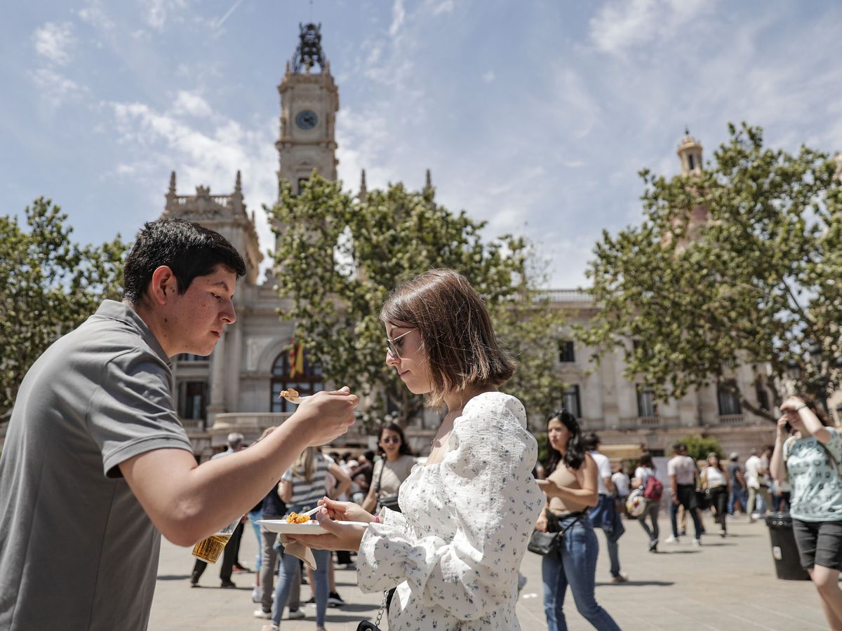 Foto: Una pareja degusta una paella para llevar frente al Ayuntamiento de Valencia. (EFE/Manuel Bruque)