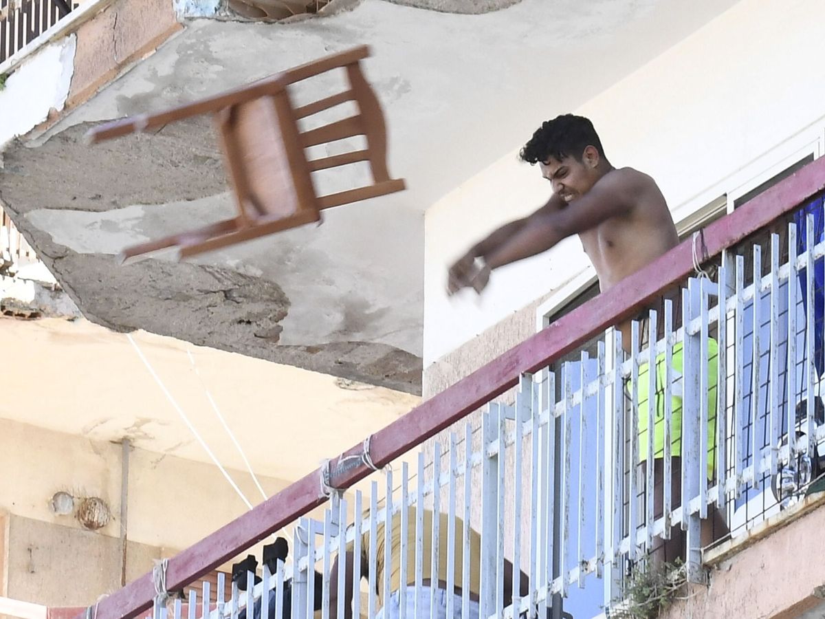Foto: un hombre tira una silla por la ventana en Mondragone, aislado por un brote. (EFE)