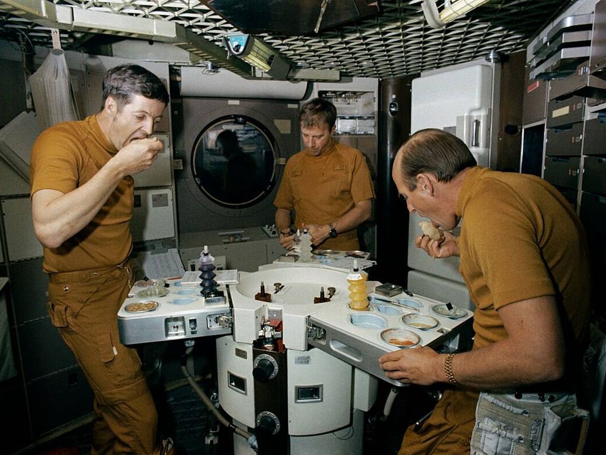 Foto: Los astronautas del Skylab 2 comiendo comida espacial en la sala de oficiales del Skylab trainer, en 1973. (Wikimedia)