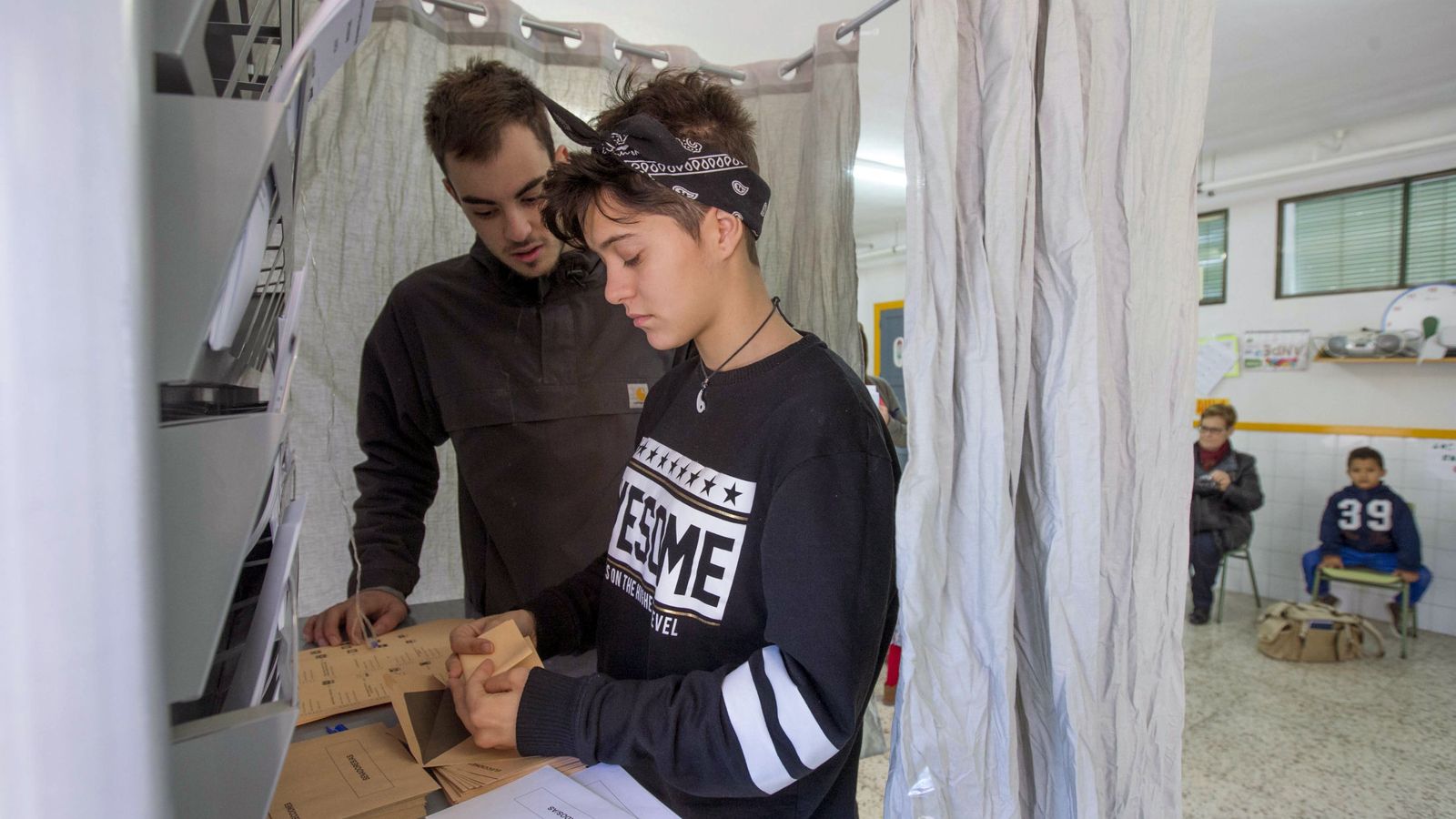 Foto: Dos jóvenes que votan por primera vez introducen las papeletas en un colegio electoral. (EFE)