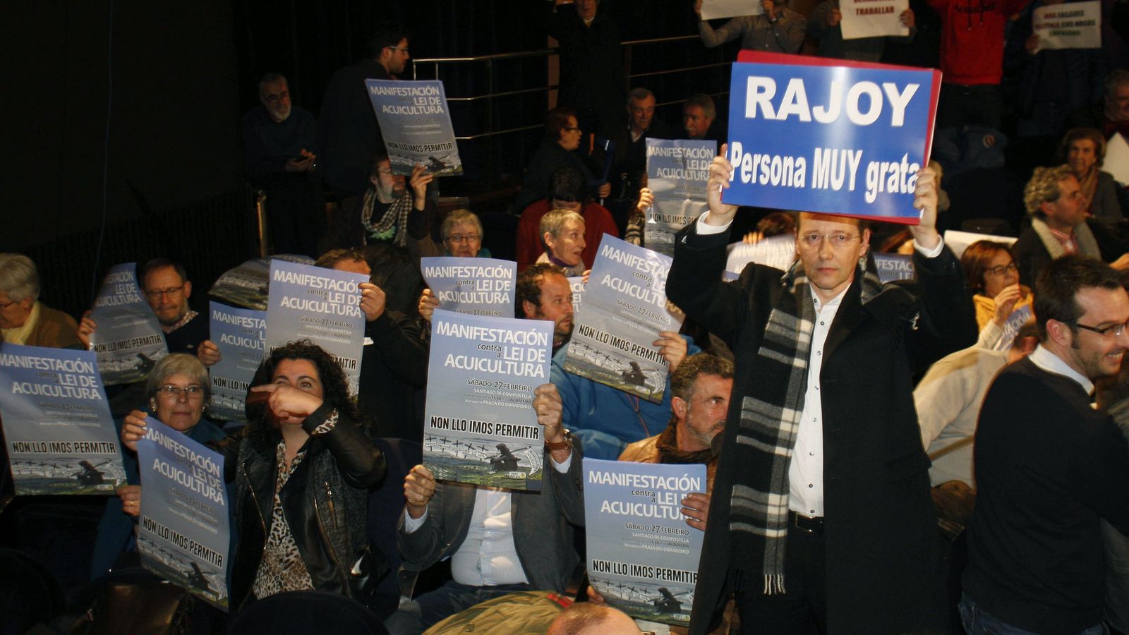 Foto: Un asistente al pleno muestra una pancarta de apoyo a Mariano Rajoy. (Efe)