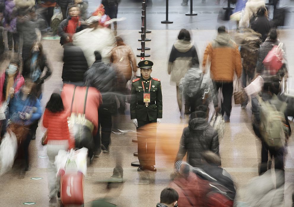 Foto: Un policía militar en medio de los pasajeros que caminan hacia sus trenes en la West Railway Station de Pekín. (Reuters)