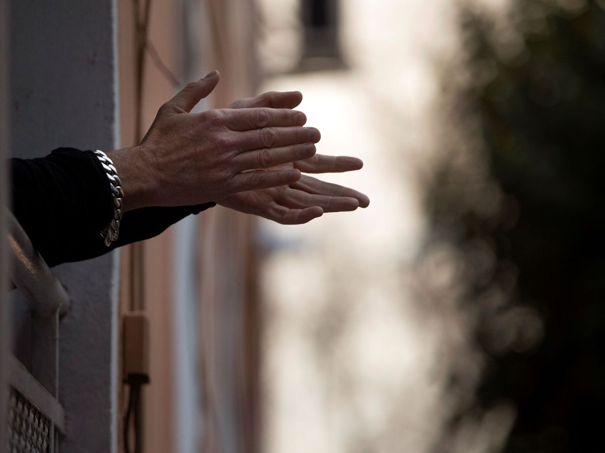 Foto: Una mujer aplaude a los sanitarios desde su ventana en Madrid. (EFE)