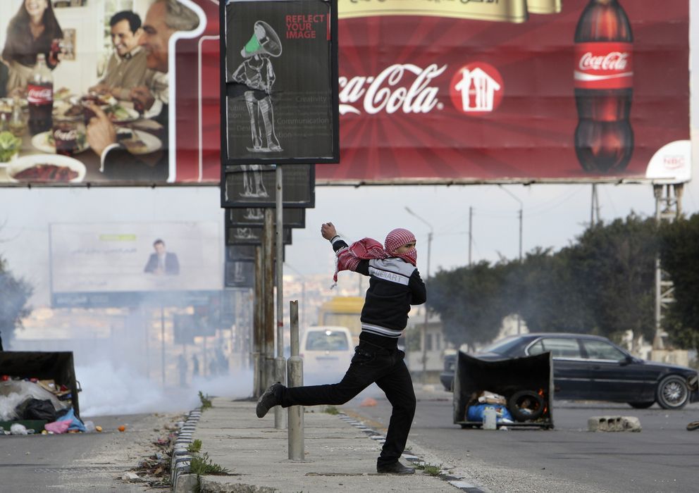 Foto: Un palestino lanza una piedra contra un agente israelí y de fondo se ve un cartel con publicidad de Coca-Cola (Reuters) 