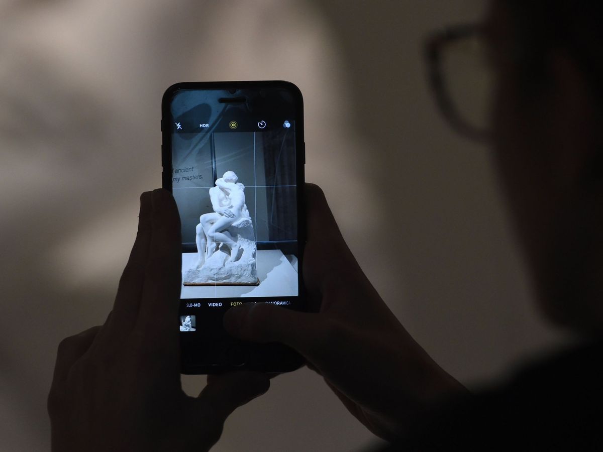 Foto: Un visitante fotografía con su móvil la escultura 'El beso' en una fotografía de archivo. (EFE/Facundo Arrizabalaga)
