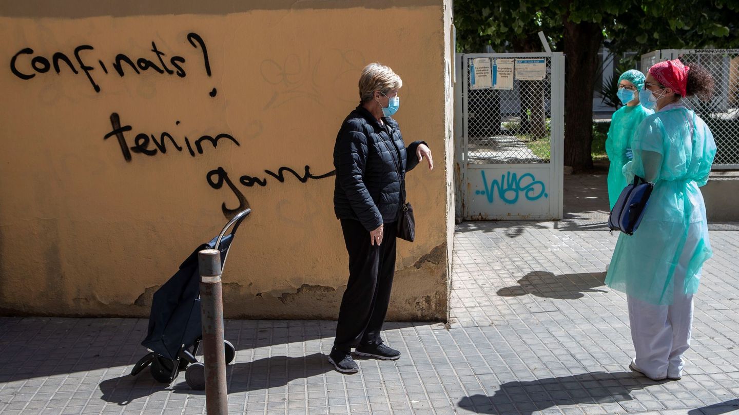 Dos enfermeras de atención domiciliaria charlan con una vecina frente al CAP del barcelonés barrio del Raval. (EFE)