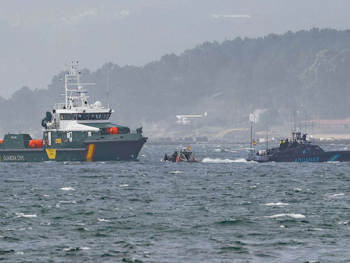 Foto: Buceadores de la Guardia Civil llevan a cabo labores de rescate junto al narcosubmarino. (EFE/Lavandeira Jr)