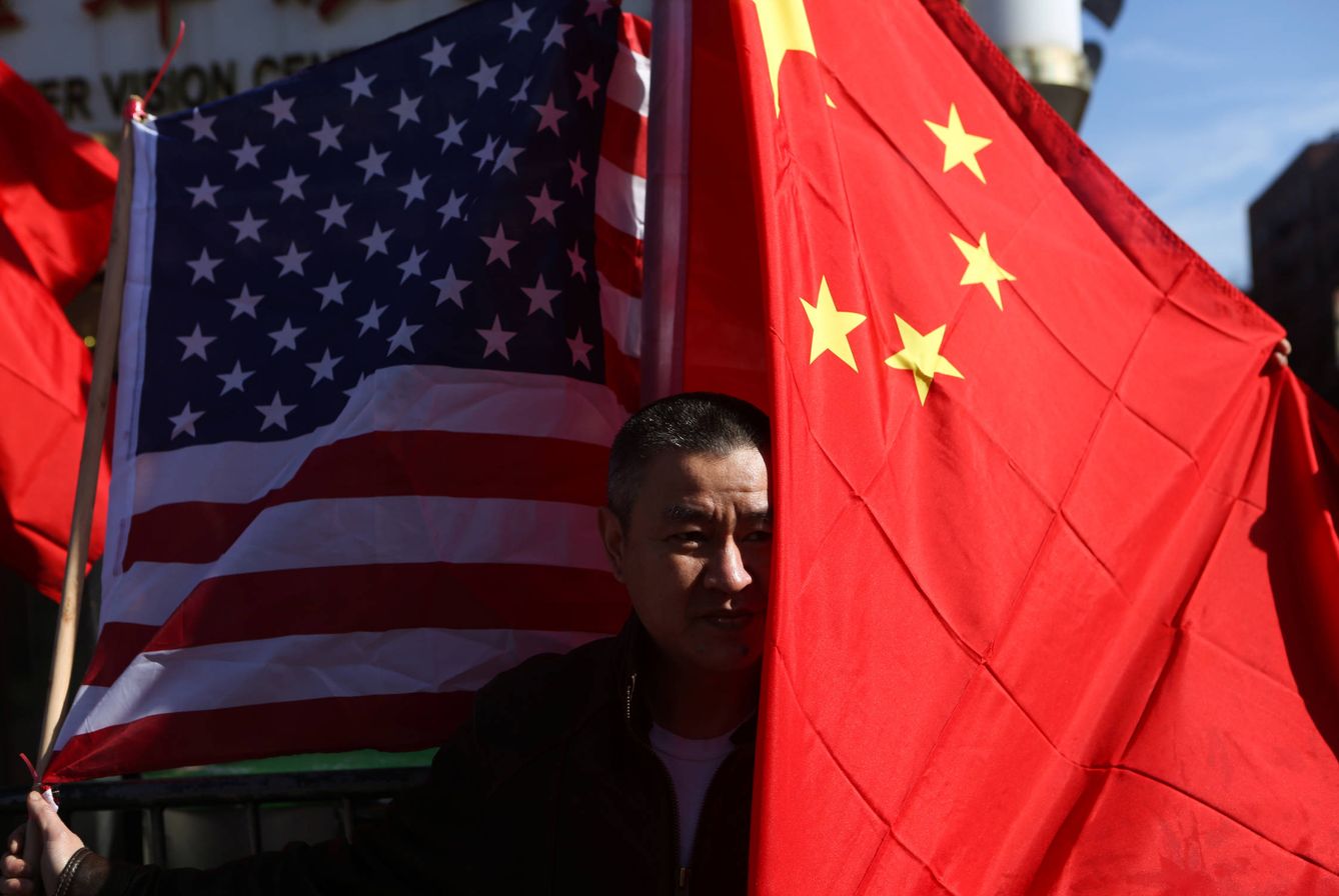 Un hombre posa con una bandera estadounidense y otra china en Queens, Nueva York. (Reuters)